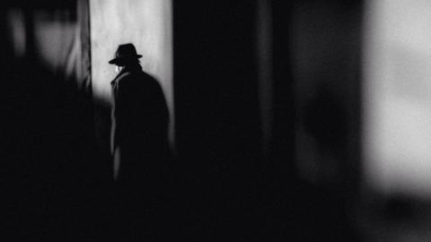 Man in hat walking on street in shadow