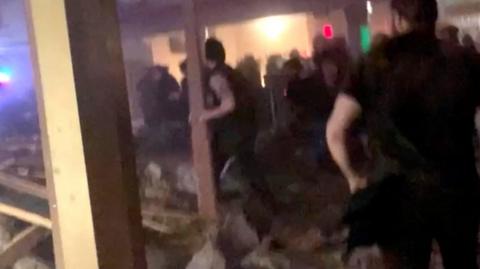 Video shows people trying to rummage through the debris from a collapsed roof at an Illinois theatre.
