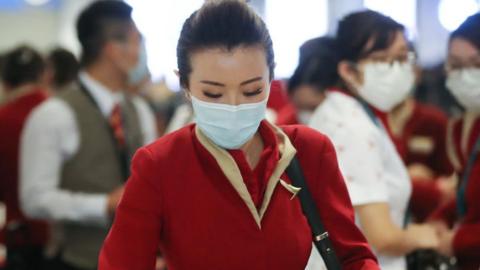 A flight crew from Cathay Pacific Airways, wearing protective masks, gather in the international terminal after arriving on a flight from Hong Kong.