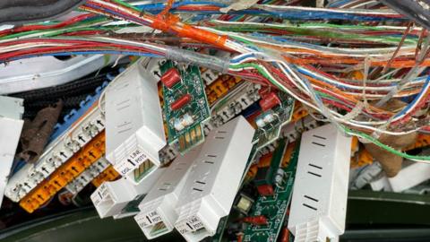 Exposed cables in damaged telecoms exchange box