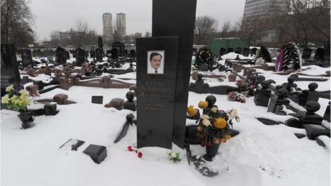A picture taken on December 7, 2012, shows snow clad grave of Russian lawyer Sergei Magnitsky with his portrait on the tomb (C) in Moscow.