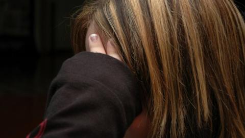 A teenager sits in a defensive posture.