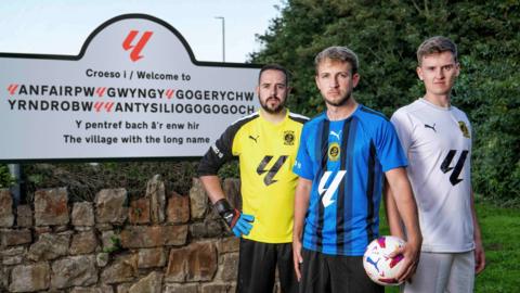 Llanfairpwll players pose in front of the village's road sign