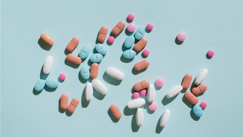 Colorful pills and capsules on blue background. Minimal medical concept. Flat lay, top view.