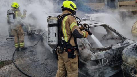 A firefighter and a burning car