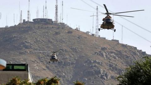 Afghan air forces helicopters fly over the site of a suicide attack, which was followed by a clash between Afghan forces and insurgents, during an attack on the Iraq embassy in Kabul, in July 2017