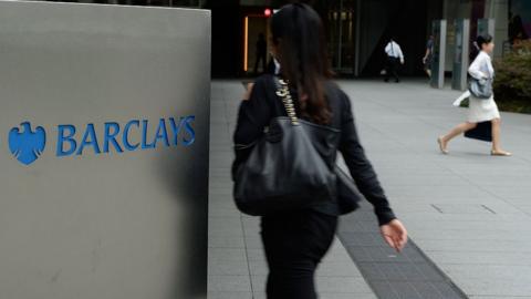People walking by a Barclays sign