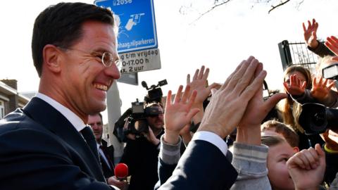 Mark Rutte high fives children after casting his vote in the Dutch general election