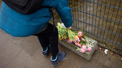 People put down flowers in front of the building where the attack happened