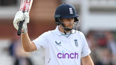 Joe Root raises his bat to the crowd after reaching 50