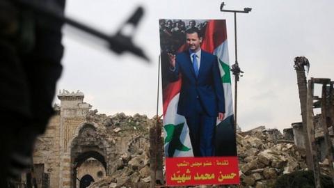 A Syrian soldier near a poster of President Assad at the old city of Aleppo, 31 January 2017