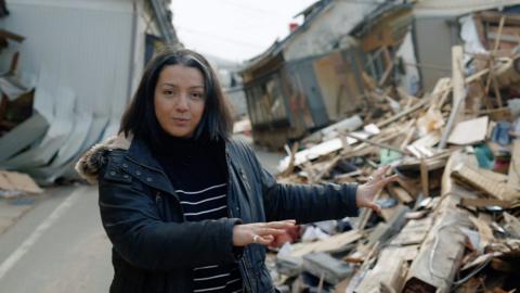 Shaimaa Khalil in front of damaged houses
