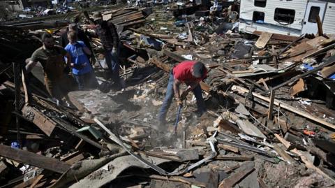 Community members and volunteers sort through the debris of a destroyed home, two days after a tornado hit Sullivan, Indiana, U.S., April 2, 2023.
