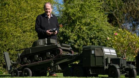 Roland Hopper with his model tank driving it in the garden via remote control