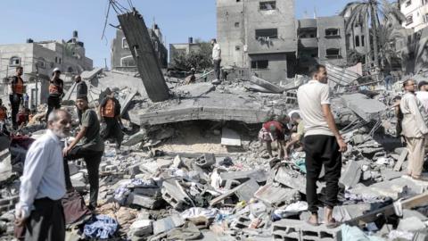 Palestinians search for victims and survivors in the rubble of a residential building leveled in an Israeli airstrike in Khan Younis refugee camp in the southern Gaza Strip.