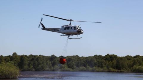 Helicopter scooping up water to combat fire