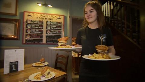 Young woman carrying plates of burgers