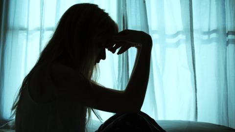 Silhouette of woman in front of curtain