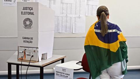 A woman wrapped in a Brazilian flag votes at a polling station in Brasilia