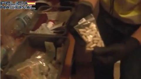 A police officer finds a bag of white pills during a raid of a house