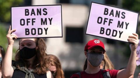 Women rights activists hold up signs as they gather at Freedom Plaza for a pre-march rally in Texas