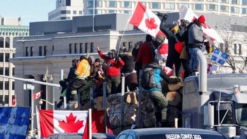 Protestors wave Canadian flags onboard a truck