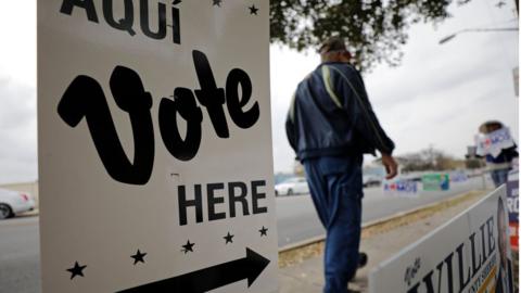 From March: Person walks by polling site in San Antonio, Texas