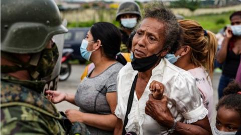 A woman holds on to a child while standing outside a prison where inmates were killed during a riot that the government described as a concerted action by criminal organisations, in Guayaquil, Ecuador February 23, 2021