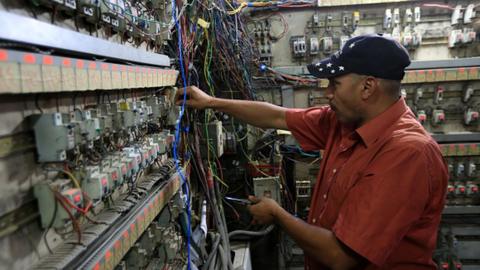 A man checks electric meter cabinet as people use generators as a solution for national power cuts in Baghdad, Iraq