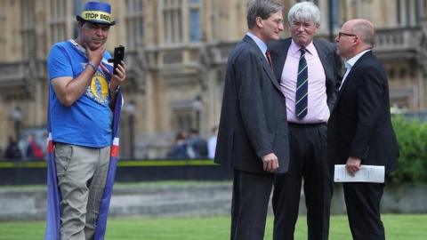 Dominic Grieve speaks to fellow Conservative MP Andrew Mitchell as anti-Brexit demonstrator looks on