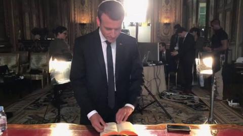 Mr Macron selects a passage at his desk in front of a large multi-person camera crew