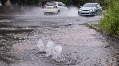 A burst water main floods a street