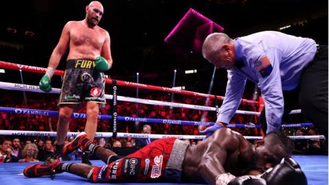 Tyson Fury stands over Deontay Wilder after a knockdown