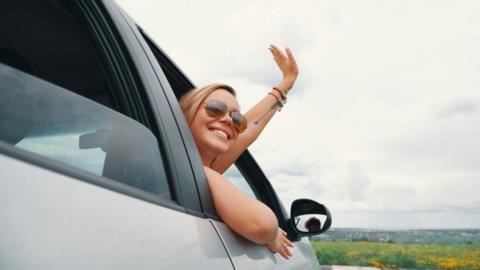 Woman waving from the window of a silver car