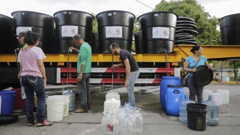 People queue for water in Caracas