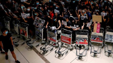 Anti-extradition bill protesters use trolleys to stop passengers from entering the security gates during a mass demonstration after a woman was shot in the eye, at the Hong Kong international airport, in Hong Kong China