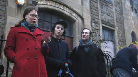 Three Jewish people singing outside the synagogue