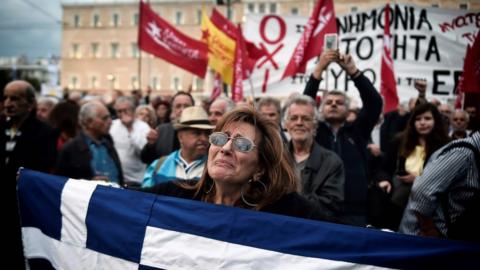 In this file photo taken on May 18, 2017 a demonstrator reacts emotionally while holding the Greek national flag outside the Greek parliament.