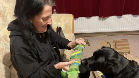 Jeanette hands a donated toy over to Koko the dog