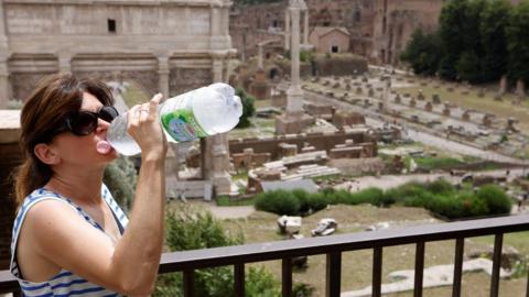 A woman drinks water near the Roman Forum during a heatwave across Italy