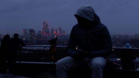 Youth sitting on park bench at dusk