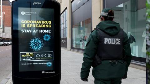 Coronavirus 'stay at home' sign with PSNI officer