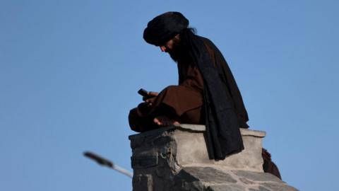 A Taliban fighter uses his phone at Wazir Akbar Khan hilltop in Kabul on August 30, 2022