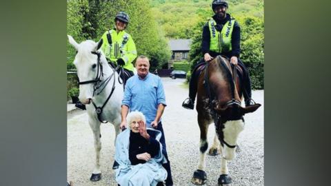 Lorna Kilham celebrating her birthday, with two police horses and officers either side of her