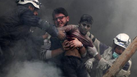 Men rescue a boy from under the rubble of a destroyed building after a reported government air strike in the rebel-held Shaar district of Aleppo, Syria (6 April 2014)
