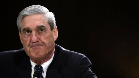 Robert Mueller in suit and tie against a black backdrop