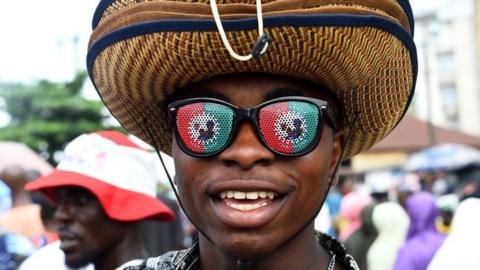 A street vendor wears goggles in the colors of the Labour Party (LP) during a campaign rally at Adamasingba Stadium in Ibadan, southwestern Nigeria, on November 23, 2022, ahead of the 2023 Nigerian presidential election