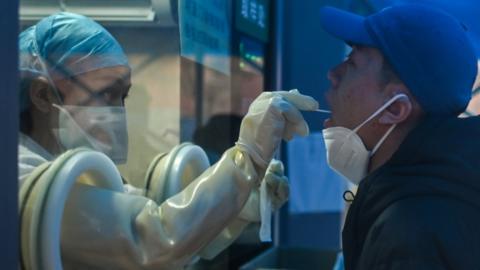 A health worker takes a swab sample from a man to test for the COVID-19 coronavirus at a hospital in Wuhan, China's central Hubei province on February 7, 2021.