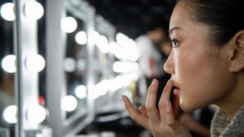 A model checks her make-up backstage before the presentation of the Rabbit-Warm collection by Zhuang Ganran during China Fashion Week in Beijing on October 30, 2018.