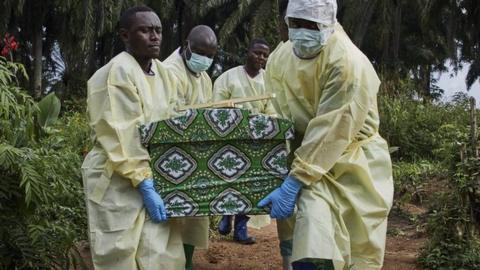 Ebola workers carrying a coffin